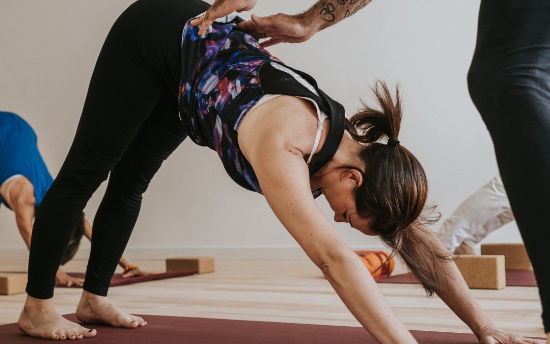 Professeure de yoga accompagnant une pratiquante dans l’adaptation d’une posture